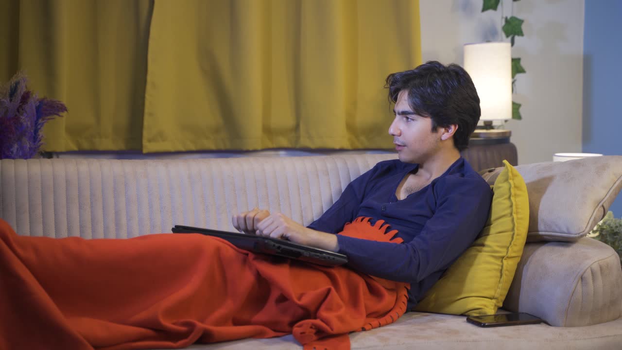 누워서 노트북을 사용하는 남자는 노트북을 긴장해서 닫습니다.