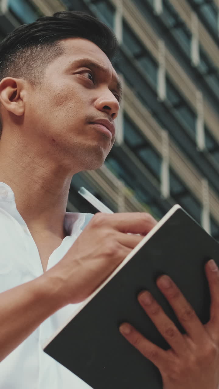 Man Writing in Notebook Outdoors