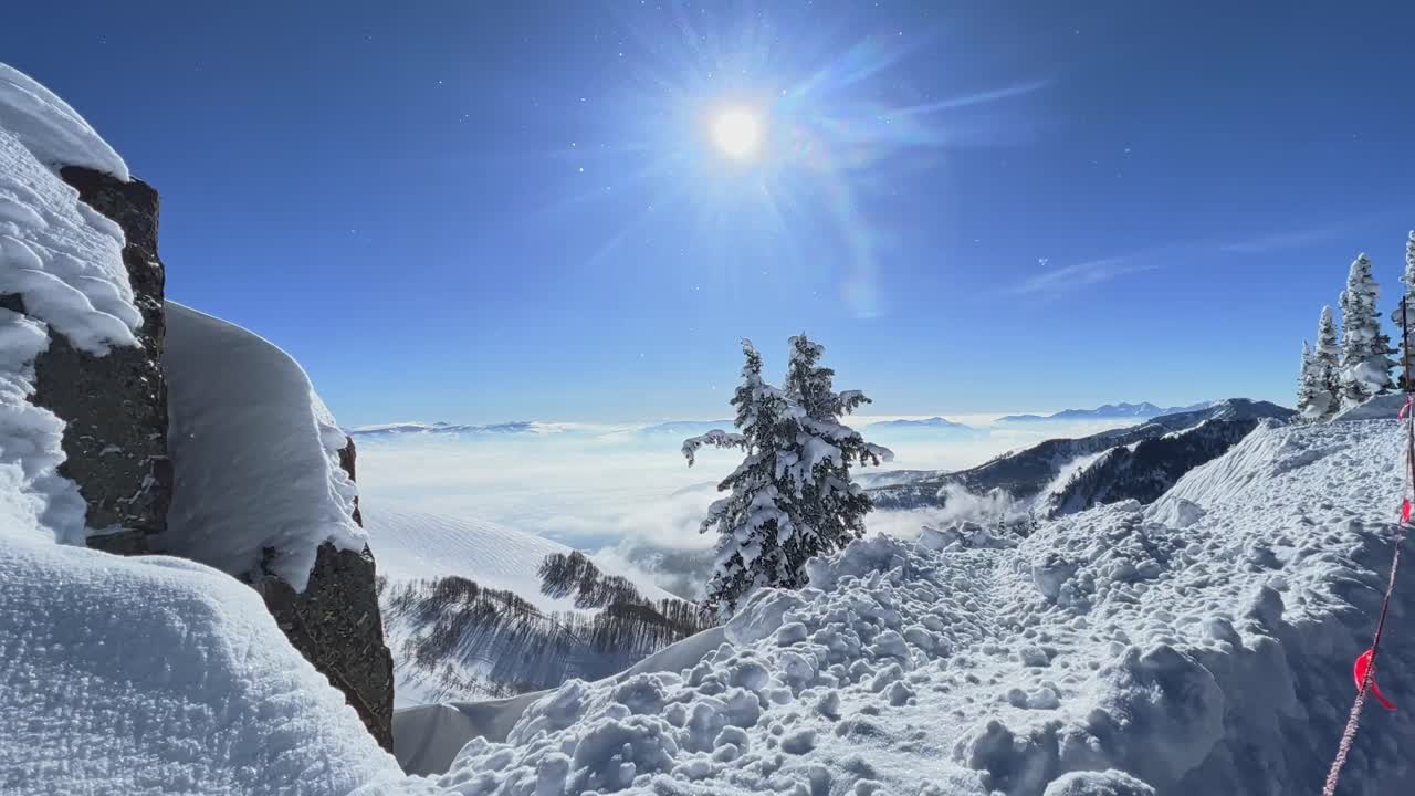 Tilt up shot of a stunning winter landscape scene looking down at a cloudy snow covered valley from the summit of a ski resort in the Rocky Mountains of Utah on a bright warm sunny spring day