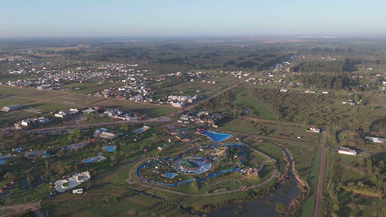 Drone shot capturing the expansive landscape of federacion city in entre rios province, featuring thermal resorts where hot baths can be enjoyed, lush greenery, and a serene river