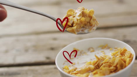 spoon lifting cornflakes with milk, heart shapes animation over breakfast scene