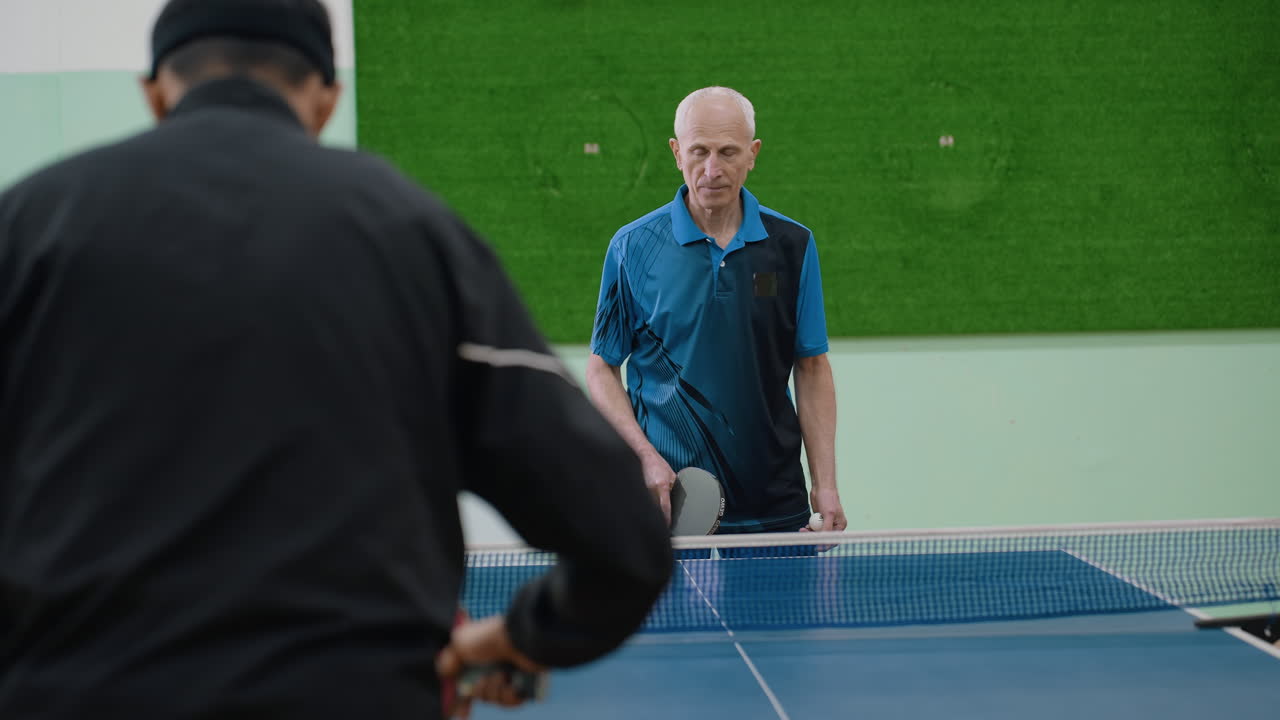 Close up back view of two athletes competing against senior coach during table tennis session, indoor training match highlighting focus