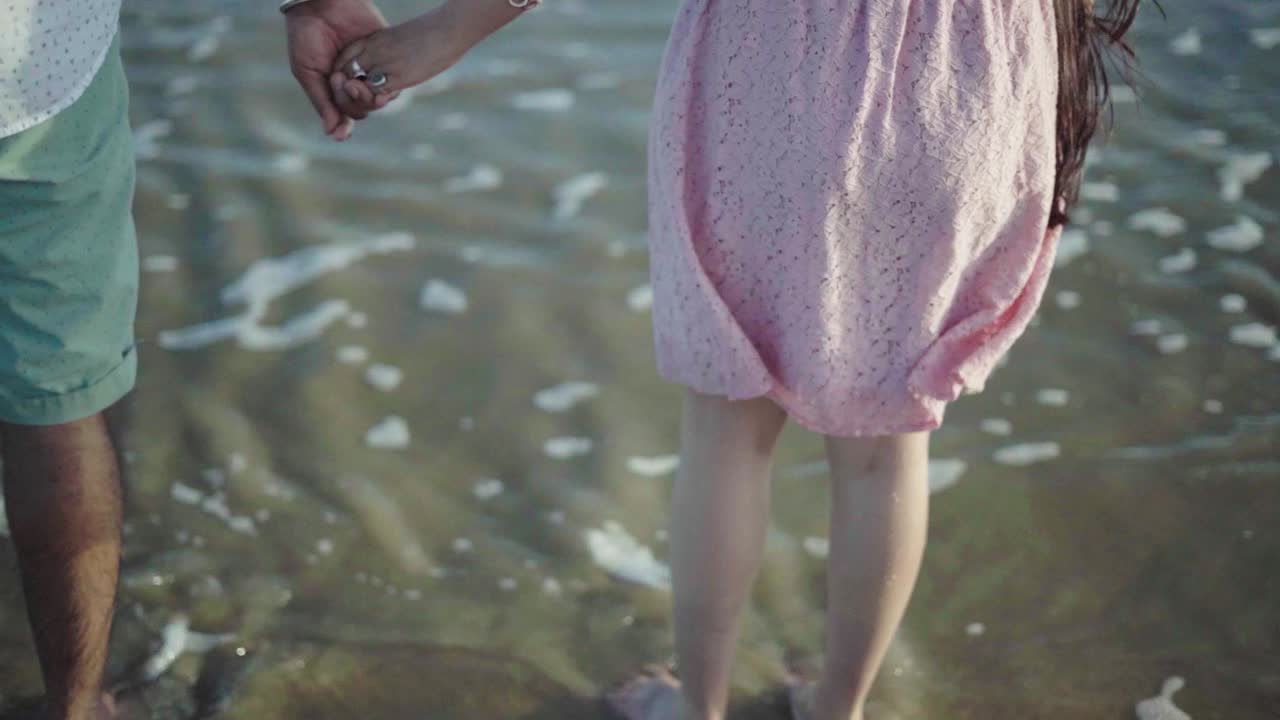 백그라운드에서 파도와 함께 손을 잡고 부부의 뒷면의 클로즈업 샷