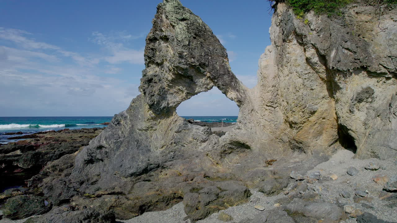 Smooth drone fly-through of the iconic Australia Rock in Narooma, NSW. Captures the natural sea-carved arch with dramatic ocean waves and striking coastal scenery