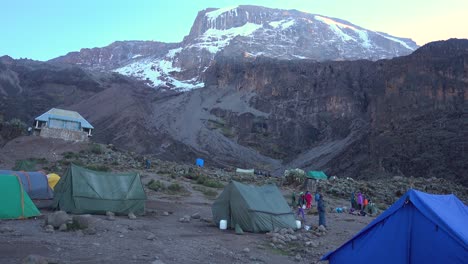 slight tilt up from a kilimanjaro hike camp with tents revealing top of mount kilimanjaro