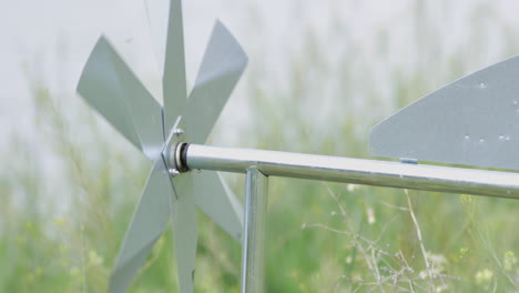 rack focus shot of a shiny stainless steel weather vane spinning steadily