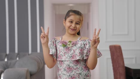 happy indian kid girl showing victory sign to the camera