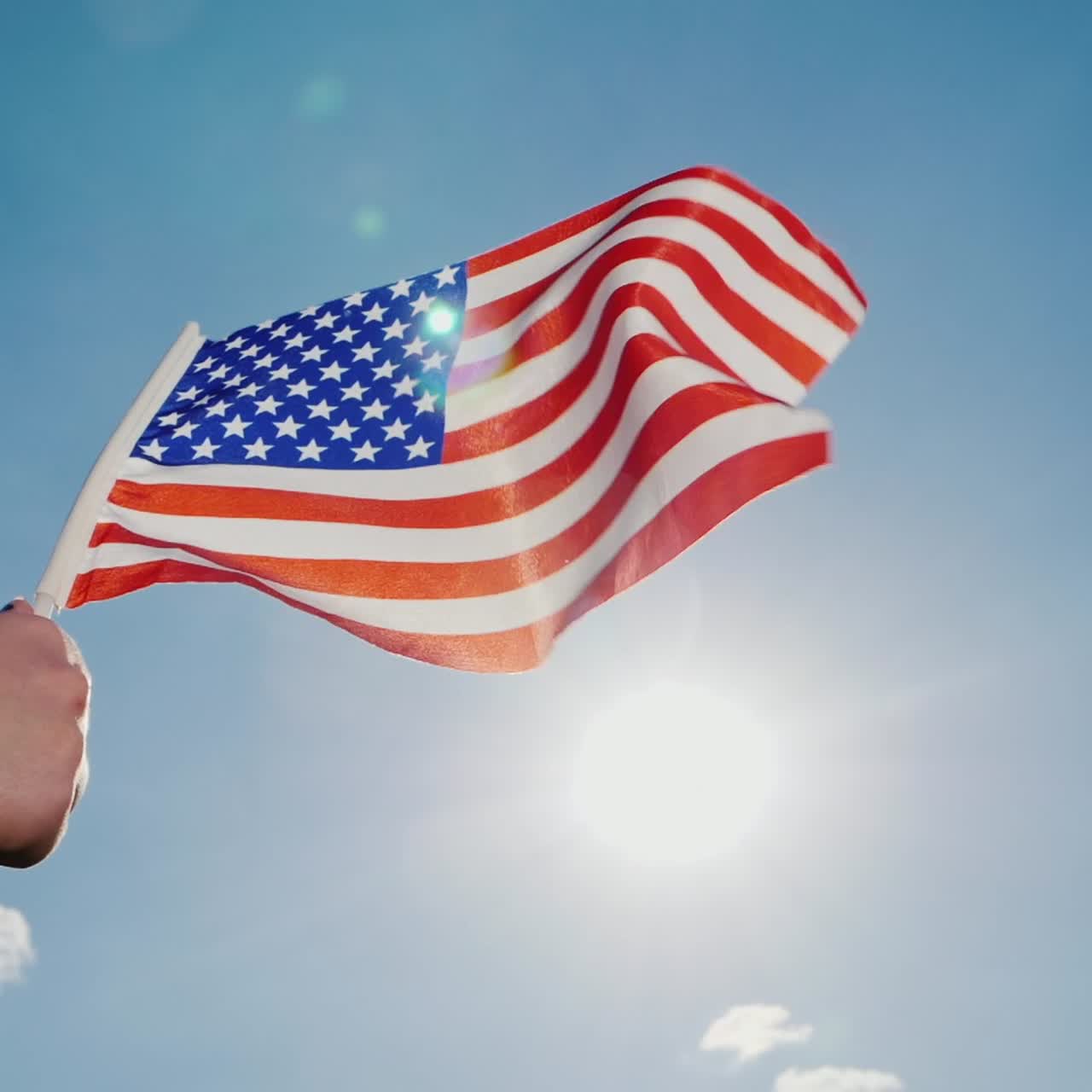Bandiera americana sullo sfondo di un cielo blu sereno e sole.