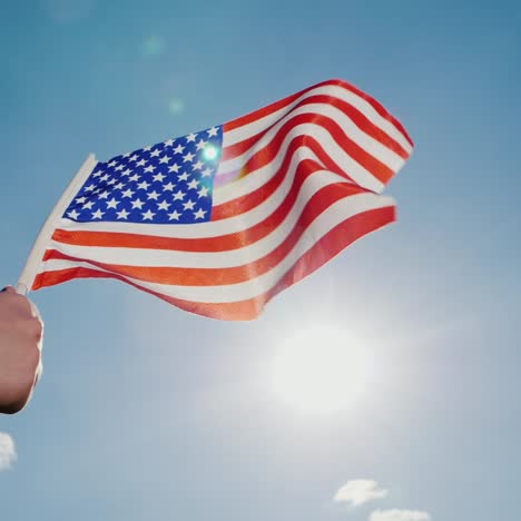 Amerikanische-Flagge-Vor-Dem-Hintergrund-Eines-Ruhigen-Blauen-Himmels-Und-Der-Sonne