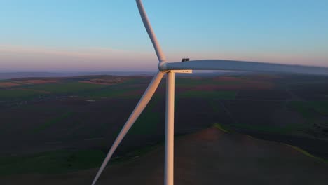 wind turbine spinning at sunset over expansive countryside, generating clean energy