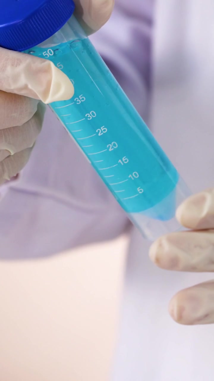 Scienziato che maneggia una provetta con liquido blu