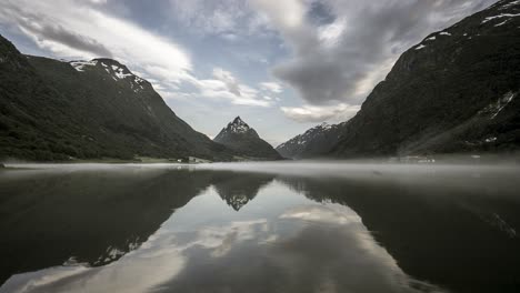 Reflection-of-clouds-and-mountains-in-misty-valley-timelapse