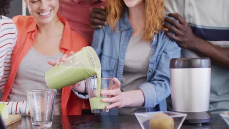 Happy-group-of-diverse-friends-preparing-healthy-drink-in-kitchen-together