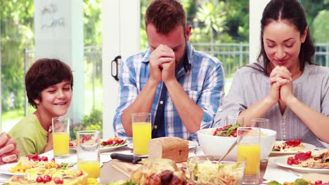 family praying before eating lunch