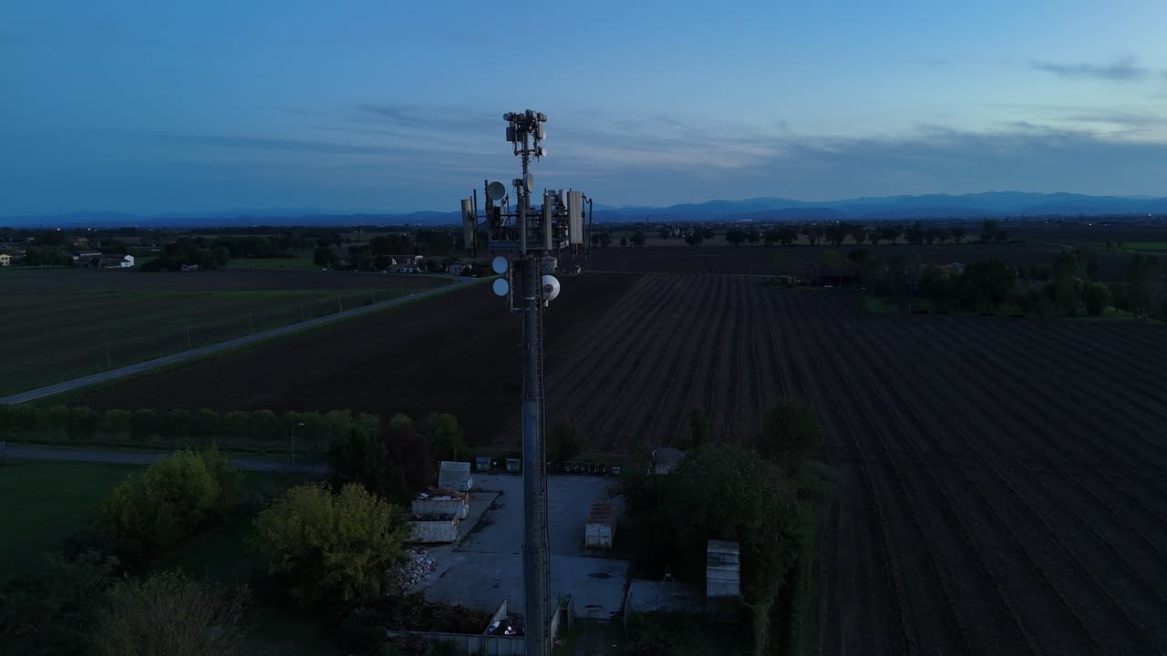 Torre ripetitore di dati cellulare che trasmette segnali di comunicazione wireless in un paesaggio rurale al crepuscolo, fornendo connettività di rete internet mobile e 5G