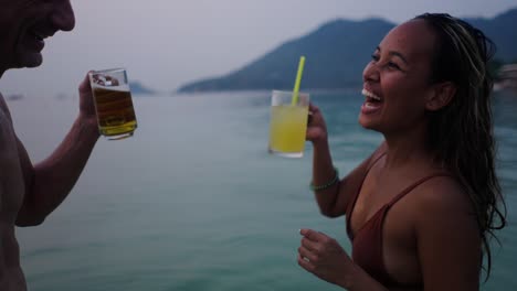happy couple enjoying drinks in the ocean at twilight