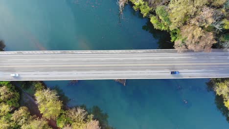 Aerial-top-down-shot-of-a-bridge-over-a-green-blue-river