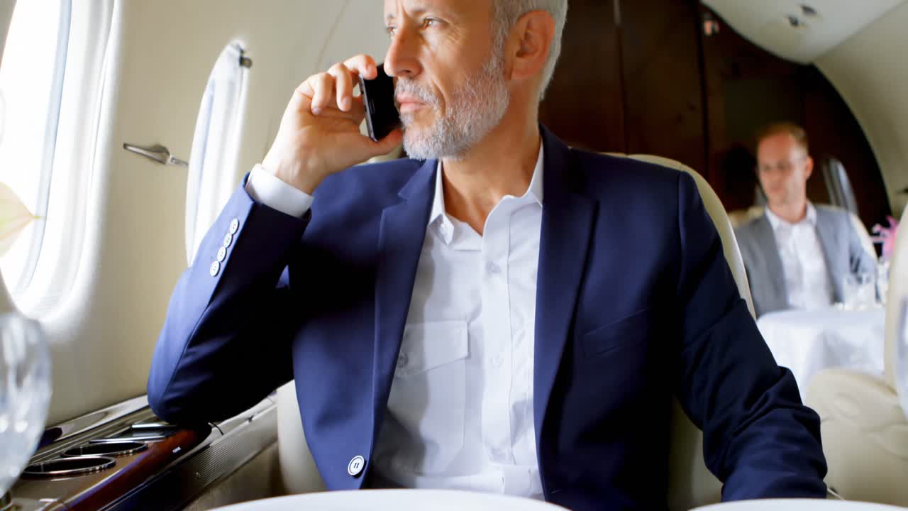 hombre de negocios hablando por teléfono móvil mientras viaja en un jet privado 4k