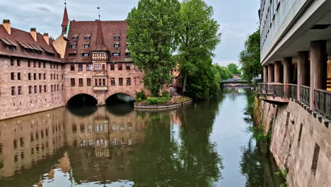 kreuzigungshof building reflected in calm pegnitz river in nurnberg, germany