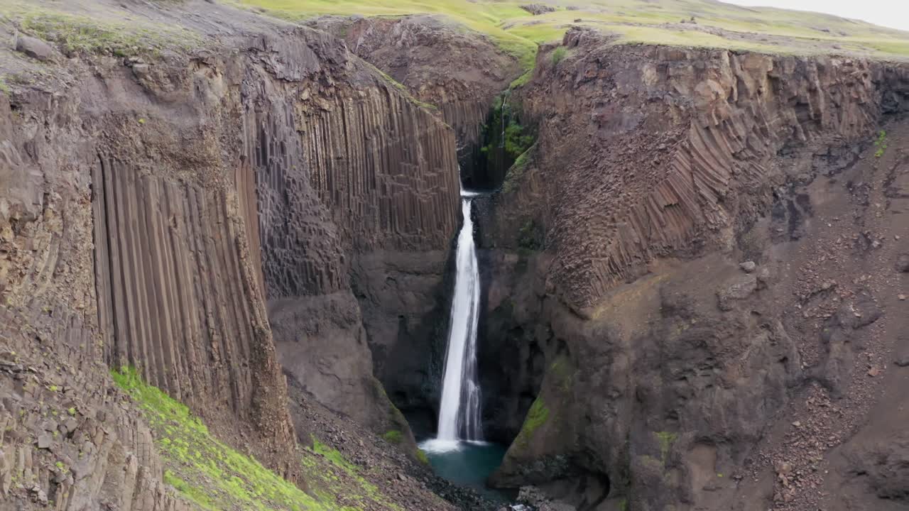 pareja sentada en una playa frente a una cascada