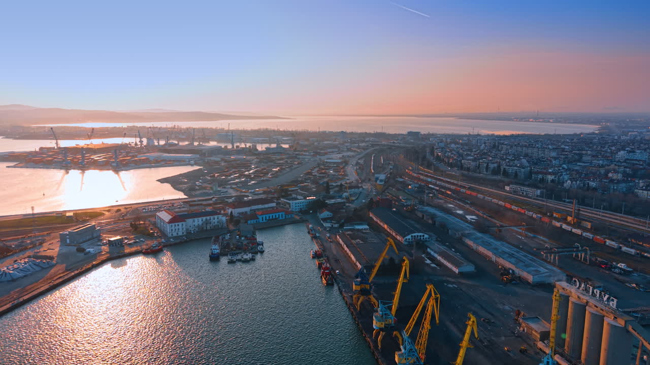 Aerial view of port railway tracks and cargo terminal. Top perspective of industrial harbor infrastructure, railway logistics and city buildings