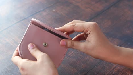 person opening a pink leather wallet to show a one hundred dollar bill