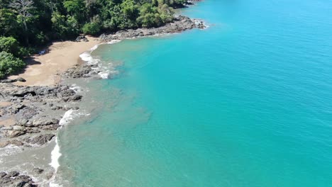 Costa-Rica-beach-drone-top-view-showing-sea,-shore-and-palm-tree-forest-in-Corcovado-National-Park-on-a-sunny-day-in-the-pacific-ocean