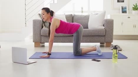 Asiatische-Frau-Auf-Der-Matte,-Die-Zu-Hause-Mit-Laptop-Trainiert