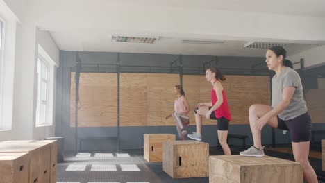 unaltered diverse women jumping on boxes and training at fitness class in gym, slow motion