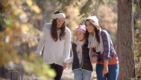 female parents walking in a forest with their daughter