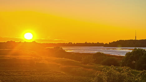 goldener stundensonnenuntergang über see und ländlicher landschaft mit schöner silhouette im hintergrund