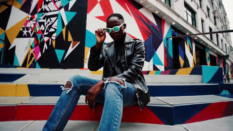 stylish man on colorful urban stairs with mural