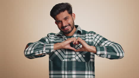 smiling hindu man makes heart gesture demonstrates love sign expresses good feelings and sympathy
