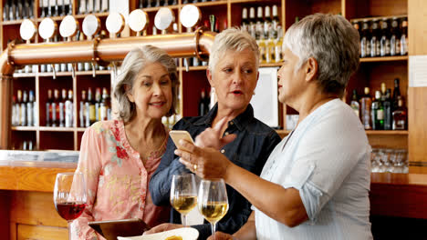 senior friends using mobile phone while having wine 4k