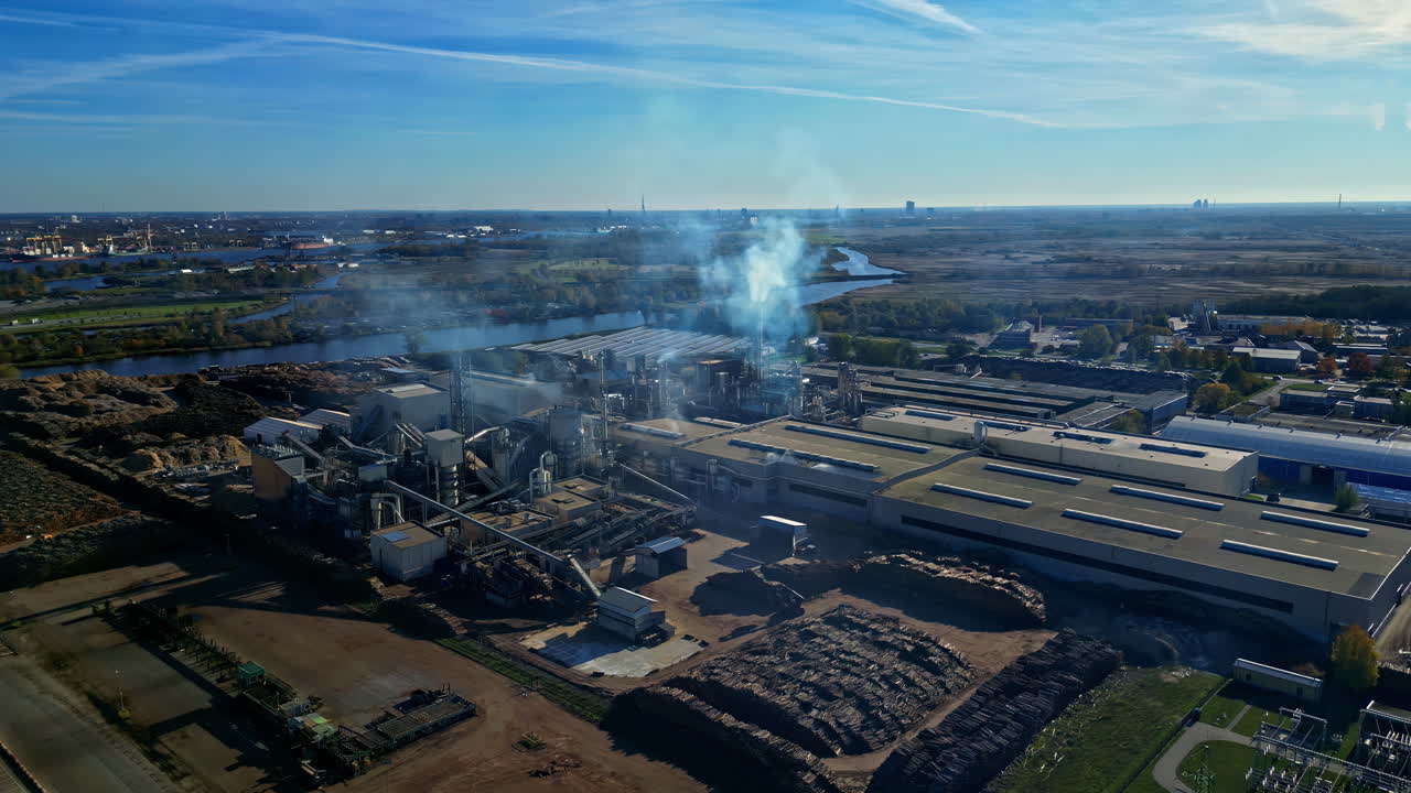 Aerial view of industrial factory with smoke and stacks under blue sky