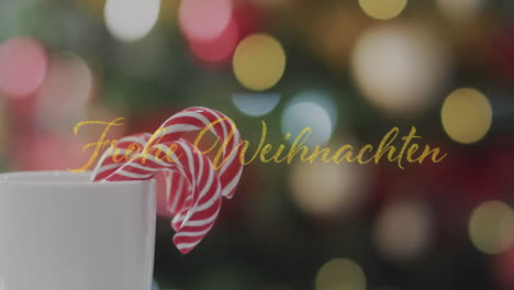 Animation-Of-Frohe-Weihnachten-Text-Over-Candy-Canes-In-Mug-Over-Spot-Lishts-Background