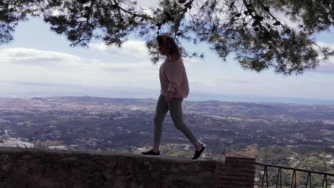 una mujer hermosa camina a través de la pared con una vista sobre españa en el fondo