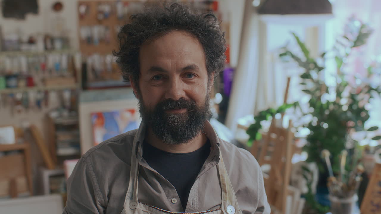 Ritratto di pittore esperto che sorride alla fotocamera in un atelier d'arte