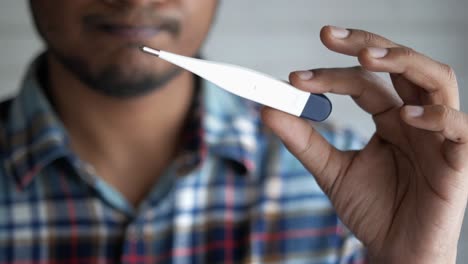 man checking body temperature with thermometer