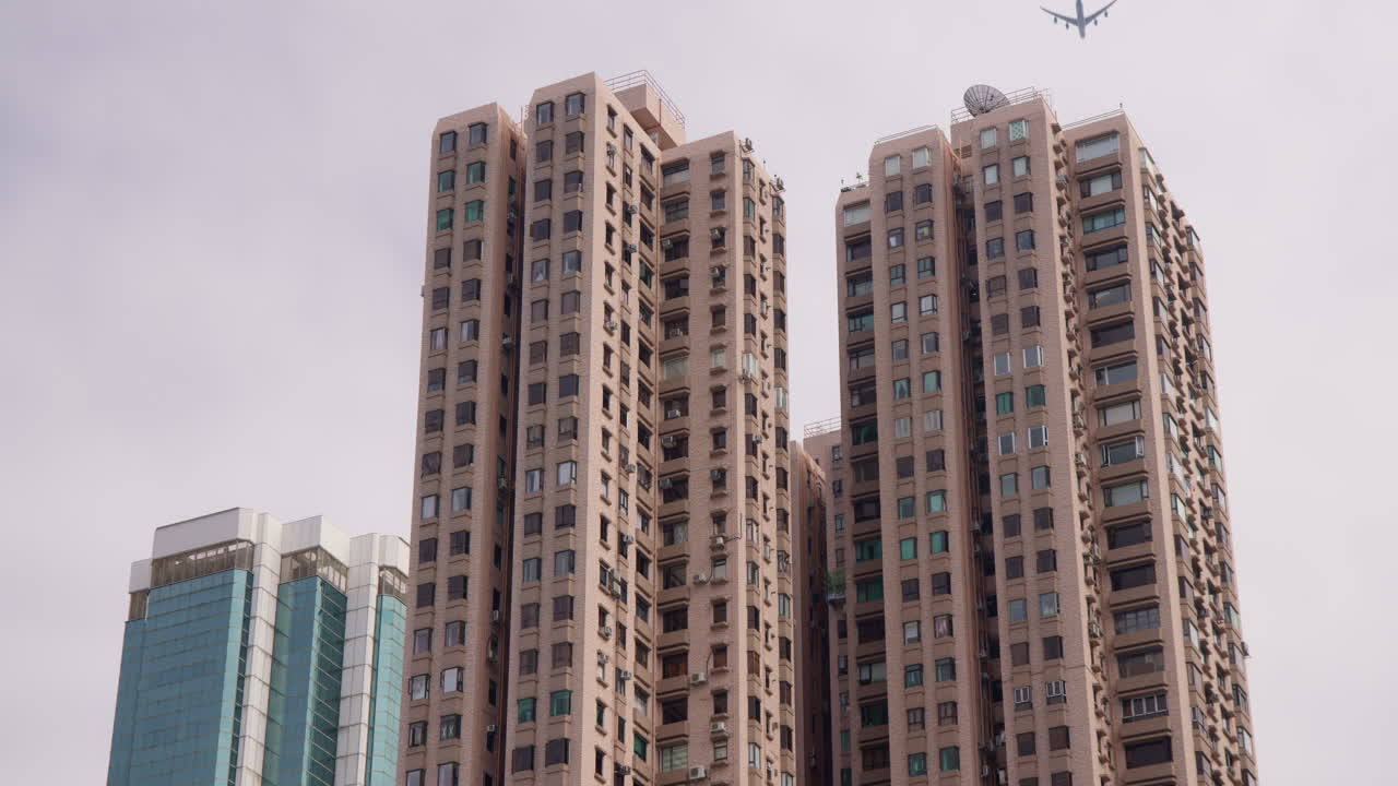 un avión volando sobre edificios residenciales de gran altura en el centro de hong kong bajo un cielo despejado