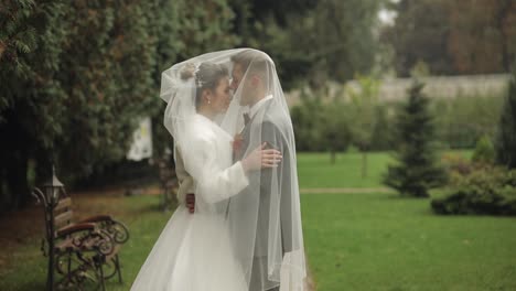 Newlyweds,-caucasian-groom-with-bride-walking,-embracing,-hugs-in-park,-wedding-couple