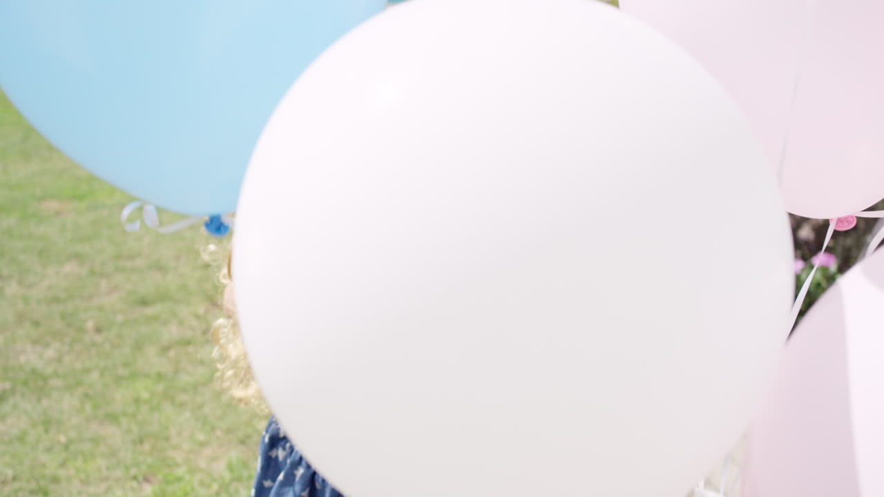 una niña rubia corriendo con globos en cámara lenta