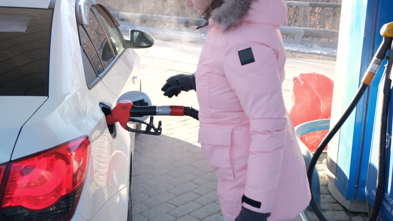 женщина кладет пистолет с бензиновым насосом в резервуар, чтобы заполнить