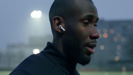 man adjusting earbuds outdoors at night