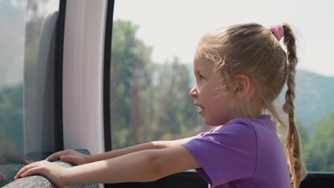 Confused-little-girl-looks-at-mountains-from-ropeway-cabin