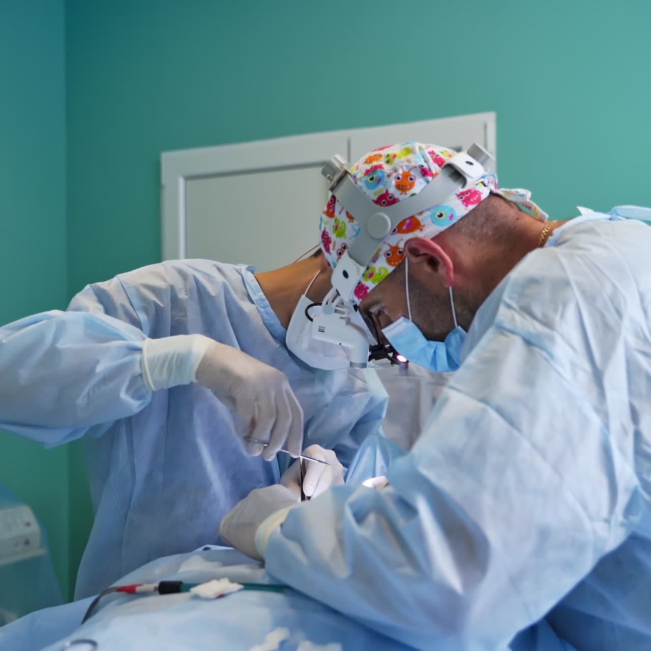 Operating theatre with surgery in process. Medical team performing operation in surgery room. Female nurses assist the male surgeons