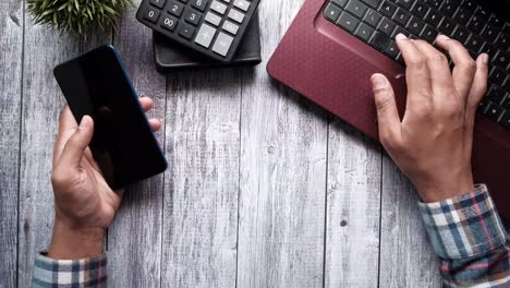 person typing on laptop at a wooden desk