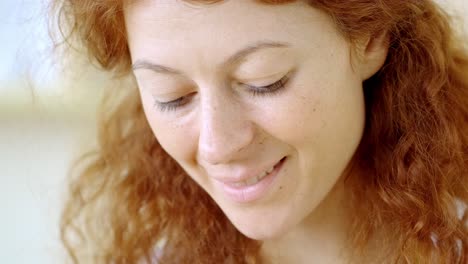 close-up of a smiling woman with red curly hair