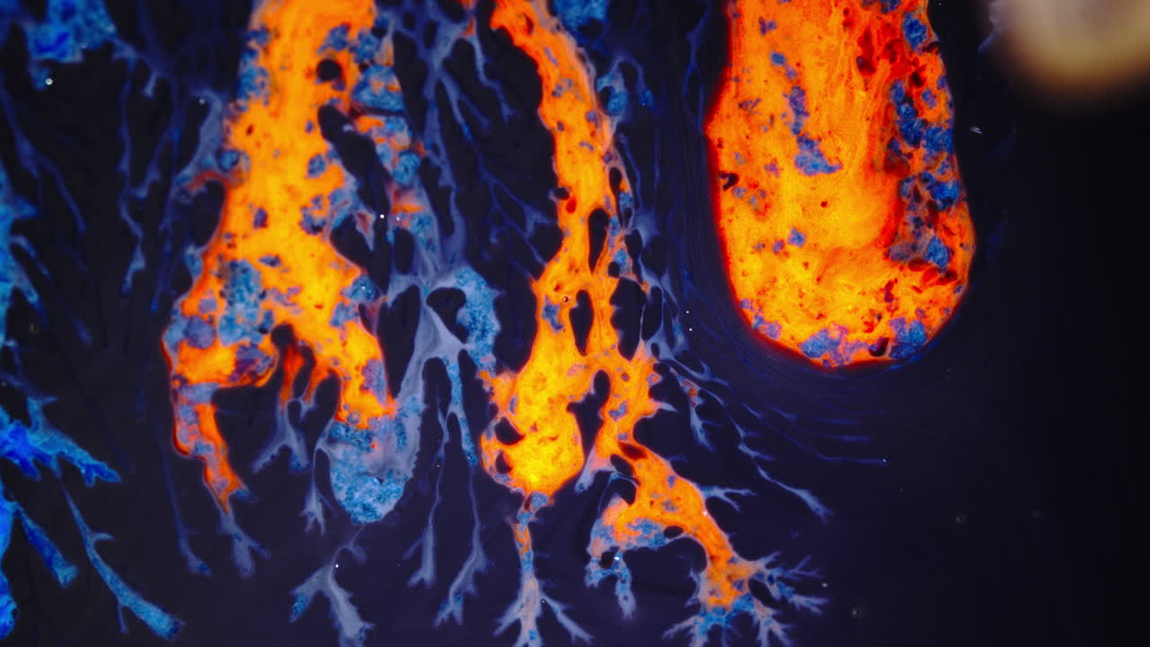 Bright ink drops mixing in water, creating colorful abstract fluid patterns in macro shot