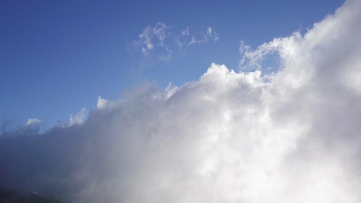Wide view of clouds moving over the slopes of a mountain on a sunny day